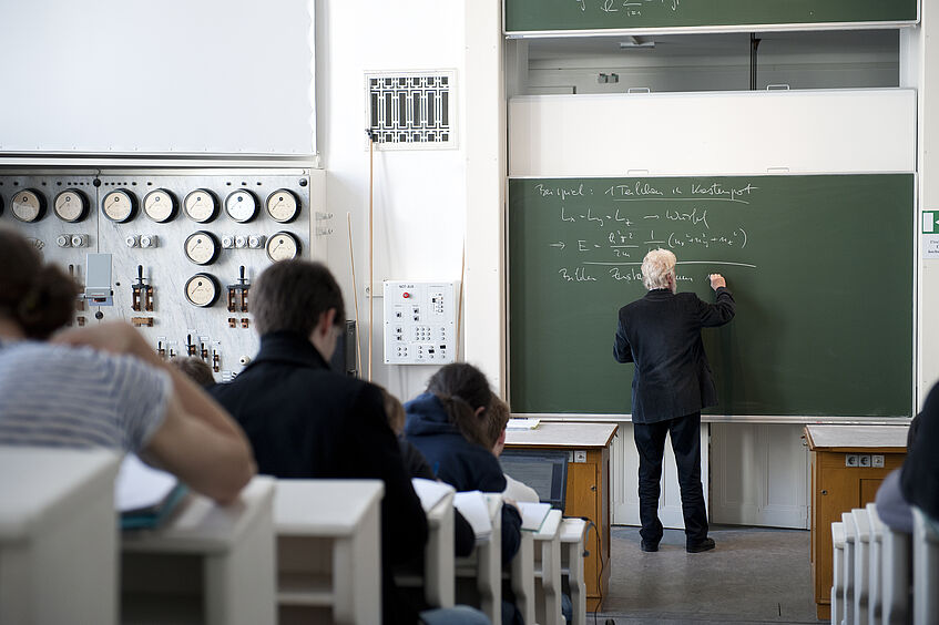 A professor writing on a blackboard.
