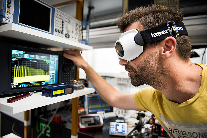 A researcher with some laser goggles looking at optical equipment.